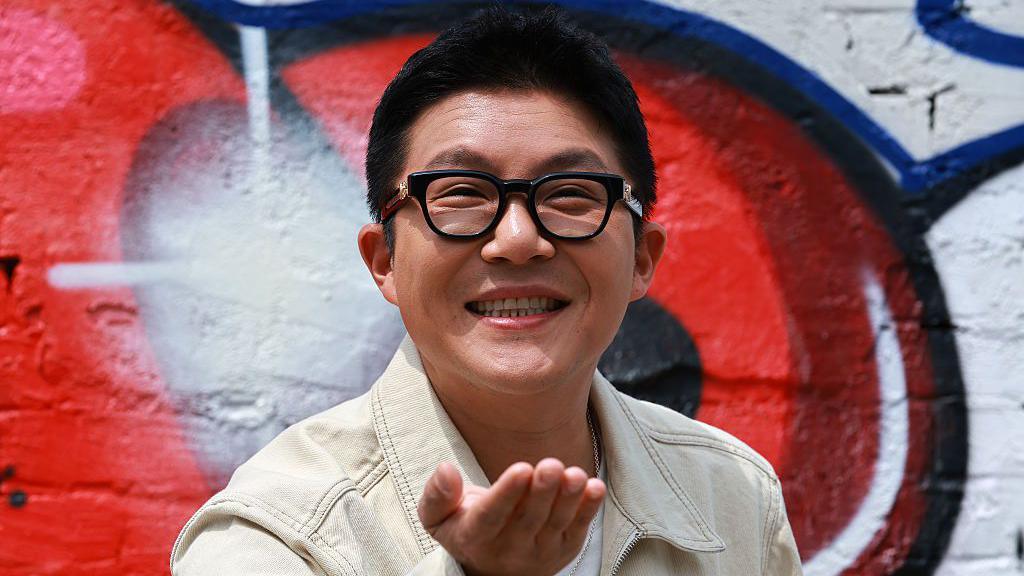 Cho Sae-ho smiling as he wears a white denim jacket and black-rimmed glasses
