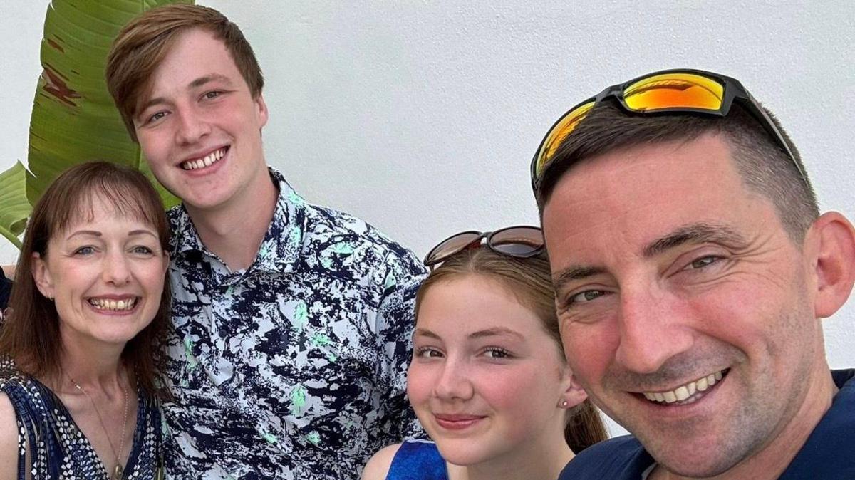 Family photo of Nicola, her children and husband. They are all smiling at the camera