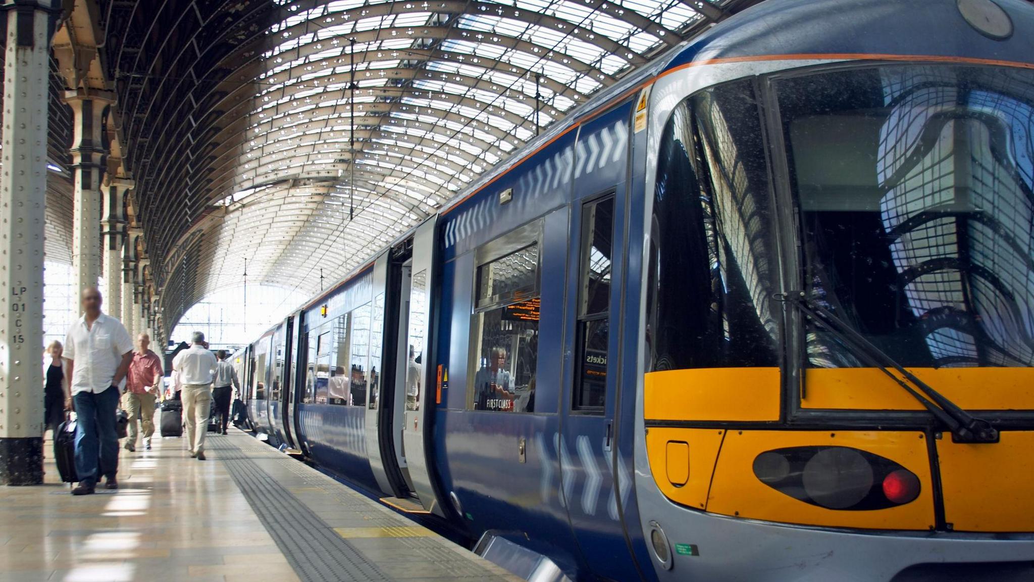 Train on platform at station in London. Passengers can be seen walking along the platform