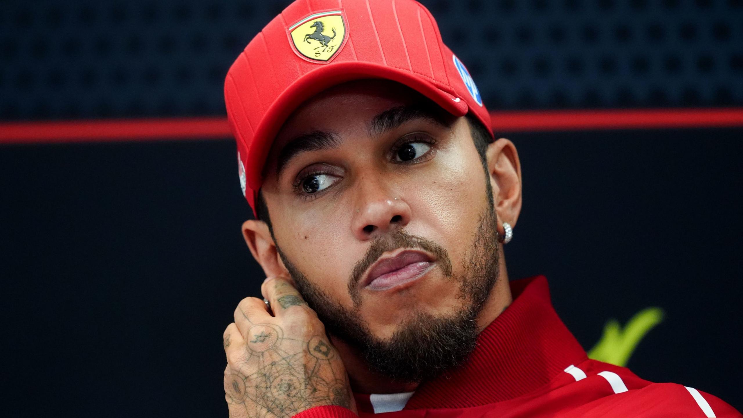 Ferrari's Lewis Hamilton adjusts an earring on his right ear in the news conference at the Qatar Grand Prix