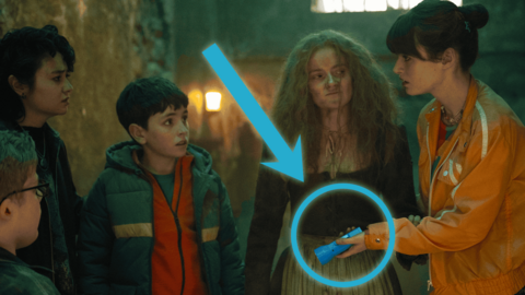 A group of kids with an old woman, a red circle is highlighting a flashlight with a big red arrow pointed towards it