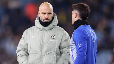 Chelsea manager Enzo Maresca with a serious expression as he talks to winger Pedro Neto on the pitch at Leeds