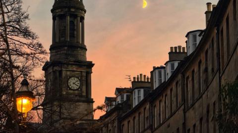 the crescent moon shining bright in the sky at sunset in Edinburgh