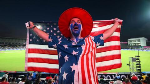 A cricket fan at the T20 World Cup in Dallas holds up the stars and stripes