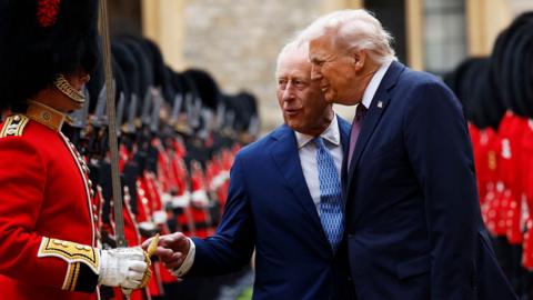 King Charles and Donald Trump smile together as they speak to a Guard of Honour during the procession at Windsor on Wednesday.
