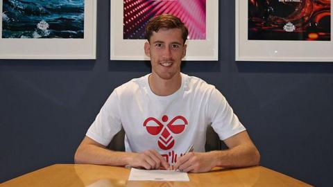 Robin Roefs signing his Sunderland contract while sitting at a table