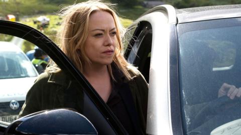 Sian Reese-Williams as DI Cadi John. She's stepping out from the driver's side of a car, looking off to the right