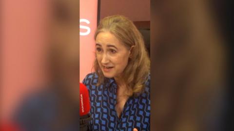 Sophie Kinsella with shoulder length hair and a blue shirt in a BBC studio.