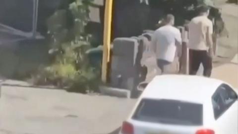 A white car approaching two men walking down the street.