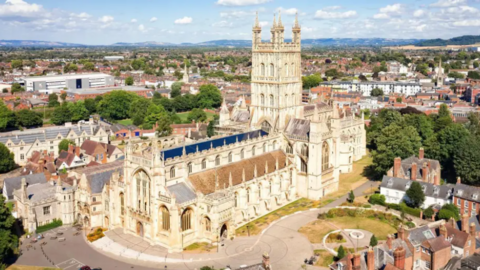 Image of Gloucester Cathedral taken from above on a sunny, clear day. Much of the city and surrounding area is also visible