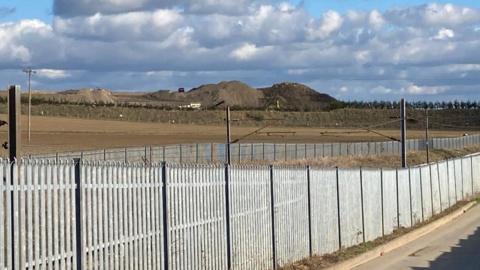 The waste recycling facility at Hacking Lane, South Elmsall. Large mounds of earth can been seen in the distance behind a metal fence.