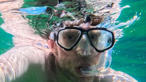 A man underwater wearing goggles and a snorkel