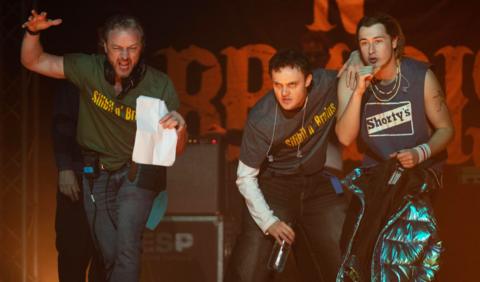James McAvoy - wearing a green T-shirt saying Silibil N' Brains and holding a piece of paper in one hand, gestures to Séamus McLean Ross and Samuel Bottomley (in character as the rappers) with direction during filming of California Schemin'.