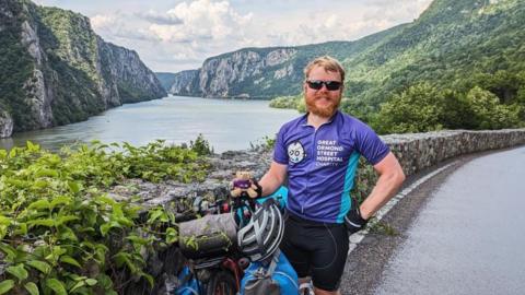 Jacob Zintel-Warner stands in front of a ravine and is wearing a Great Ormond Street Hospital Charity t-shirt.