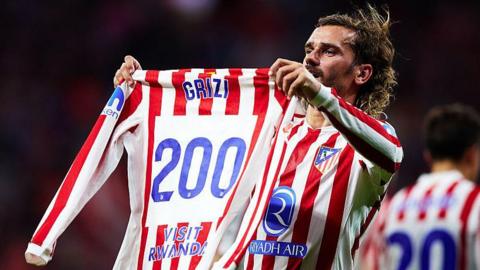 Antoine Griezmann holds 'Grizi 200' Atletico Madrid shirt up