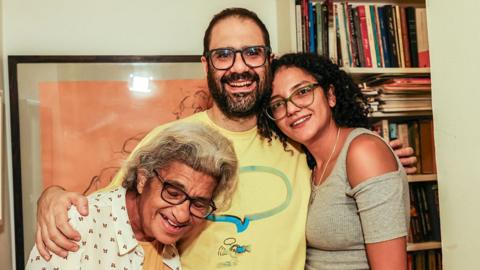 British-Egyptian activist Alaa Abdel Fattah hugs his mother and sister. The two women grin widely.