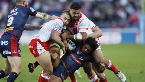 A St Helens player is rugby tackled by two Hull KR players as he tries to hold onto the ball