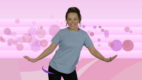 Presenter Evie Pickerill standing with her arms open wide. Backdrop of pink shapes by an athletics track.