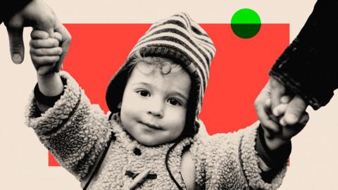 A child wearing a coat and hat, holding hands with their parents