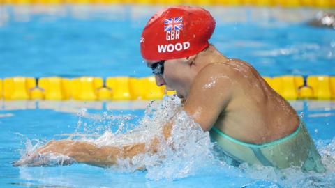 Abbie Wood swimming the breaststroke wearing a red cap