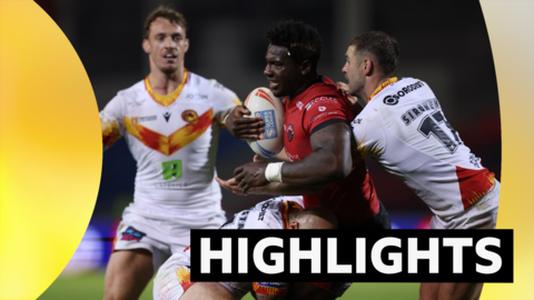 A Salford player tackled in his legs and by another player behind as he holds the ball