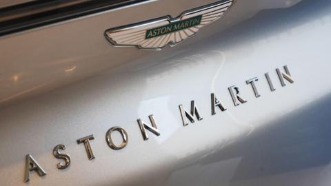 The words Aston Martin are written on a car in 3D lettering with the Aston Martin logo above.