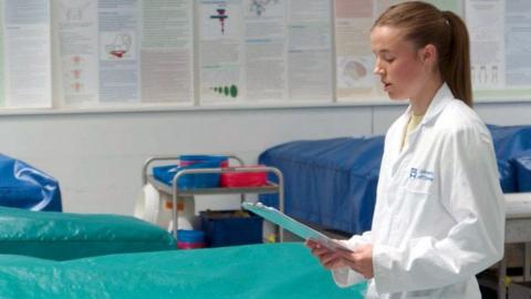 Young female medical student reading from a clipboard
