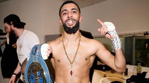 Shabaz Masoud smiles holding up his European belt