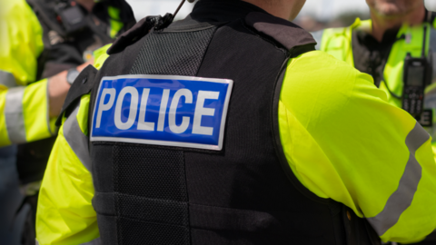 A shot of a police officer's back showing the word police written on the back of his protective vest