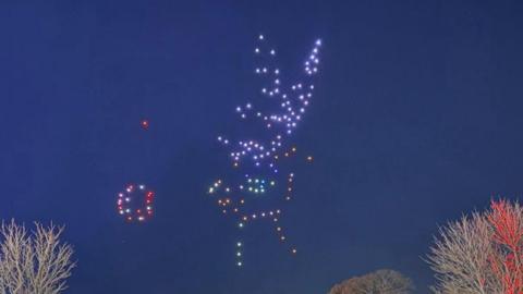 People standing in the Ardingly South of England showground look at an image of a reindeer created in the sky by drones.
