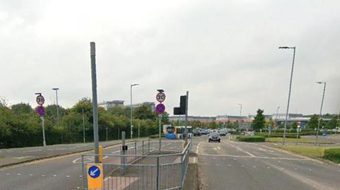 Google street view image of the traffic lights on the road, with the main hospital building seen in the distance.