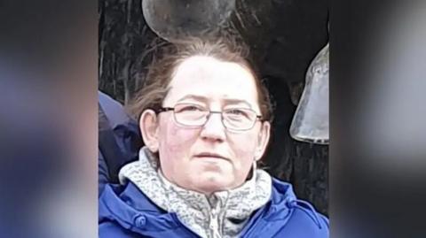 A head and shoulders picture of Marta Bednarczyk, who has a blue coat and a fleece on. She has glasses and brown or ginger hair tied back, looking towards the camera.