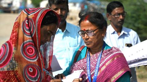 Booth Level Officers (BLOs) distribute enumeration forms as a part of the Election Commission of India's Special Intensive Revision (SIR), at a fisherman's village on the Mousuni Island in West Bengal on November 10, 2025.