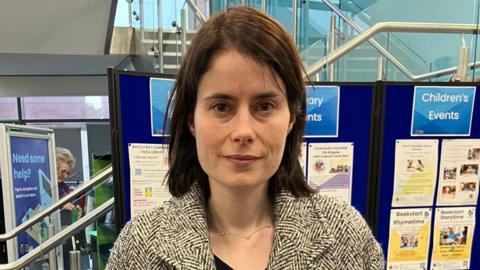 Hannah Griffiths at a consultation event for residents which discusses the housing scheme. She is wearing a black and white coat and has shoulder-length brown hair.