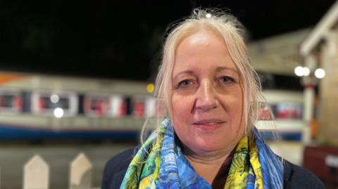 Middle-aged woman with blonde hair and a bright scarf