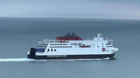 A closeup of Manxman, a large navy and white ferry as it makes its way across the sea.