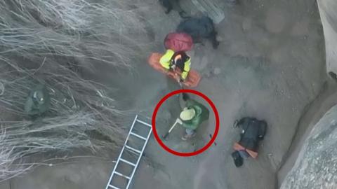 Ladders works to rescue a hiker stuck in quicksand (circled).