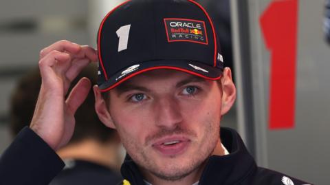 A close-up image of Max Verstappen wearing a Red Bull Racing cap which has '1' stitched into the front