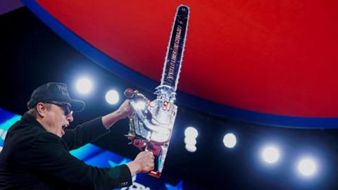 Elon Musk holds up a chainsaw onstage during the Conservative Political Action Conference (CPAC) in National Harbor, Maryland, on 20 February 2025