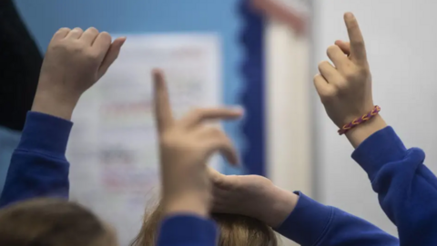 Children's hands in the air in a school setting