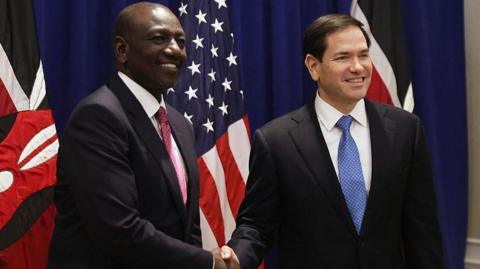 US Secretary of State Marco Rubio (R) and Kenya's president William Ruto (L) shaking hands with Kenyan and the US flags on the background