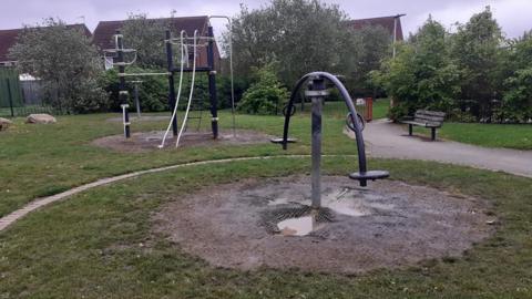 Play equipment at Kingswood Park with mud and puddles of water underneath them