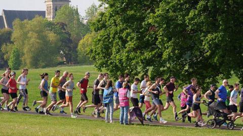 Runners running through a park at parkrun