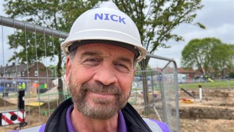 Nick Knowles smiling at the camera with his name written on his hard hat
