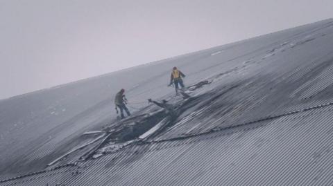 People inspect the damage to the radiation containment shield of Reactor 4 at the Chernobyl nuclear power plant following a drone strike