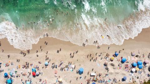 In an aerial view, people celebrate the Fourth of July along the coast of La Jolla's Windansea Beach on a warm summer day on July 4, 2023 in San Diego, California