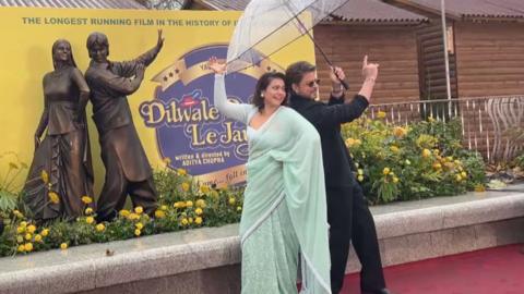 Shah Rukh Khan and Kajol pose in front of statue in London