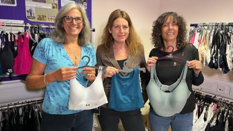 Three women holding up bras