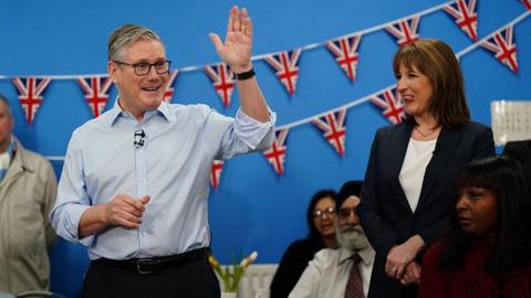 Britain's Prime Minister Keir Starmer (L) speaks with guests as Chancellor of the Exchequer Rachel Reeves (R) looks on, during a visit to the Benn Partnership community centre in Rugby, in central England on 27 November 2025.