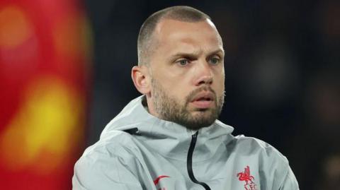 Assistant coach John Heitinga watches Liverpool warm up before a Champions League game